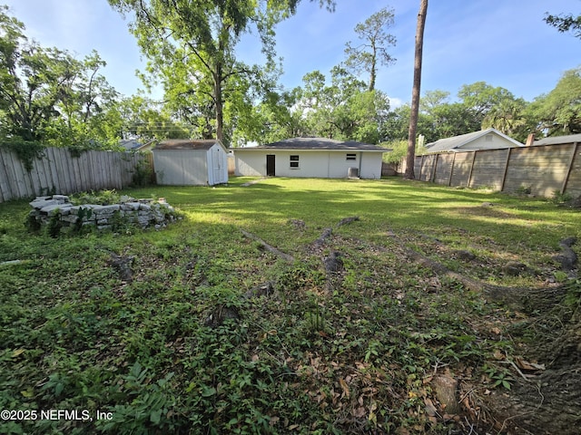 view of yard with an outdoor structure, a fenced backyard, and a storage unit