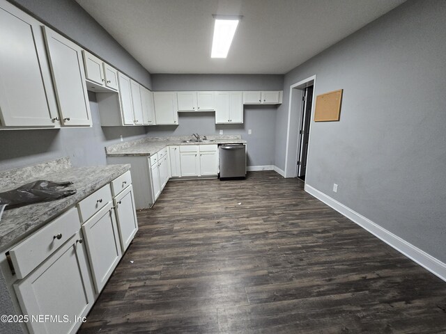 kitchen featuring baseboards, a sink, dishwasher, and white cabinets