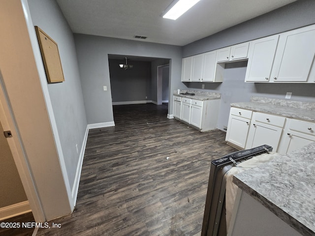 kitchen featuring visible vents, dark wood finished floors, baseboards, white cabinets, and a notable chandelier