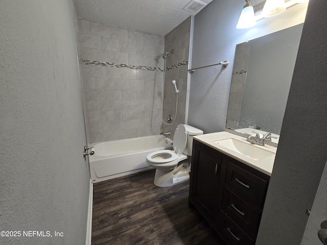 bathroom featuring a textured wall, vanity, toilet, wood finished floors, and visible vents