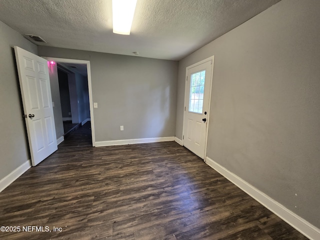 unfurnished room with baseboards, a textured ceiling, and dark wood finished floors