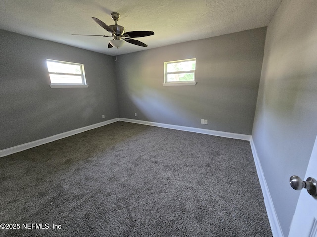 spare room with baseboards, plenty of natural light, dark colored carpet, and ceiling fan