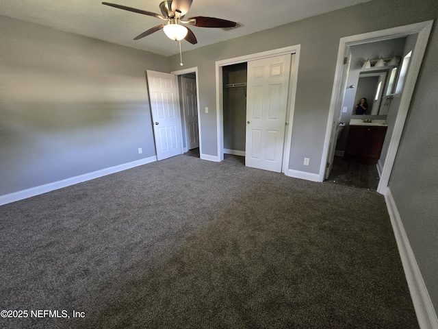 unfurnished bedroom featuring ensuite bath, dark colored carpet, a ceiling fan, baseboards, and a closet