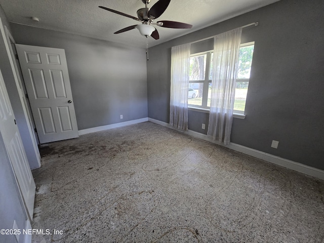 empty room with a ceiling fan, baseboards, and a textured ceiling