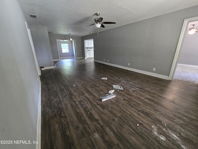 unfurnished living room with dark wood-type flooring, baseboards, ceiling fan, and visible vents
