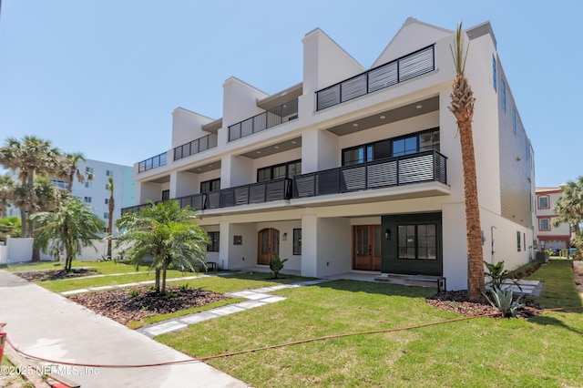 view of front facade featuring a balcony, stucco siding, and a front yard