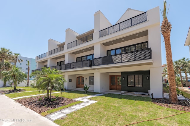 view of front of property with french doors, stucco siding, and a front lawn