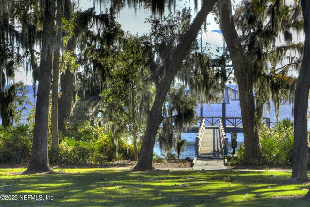 view of dock featuring a lawn and a water view