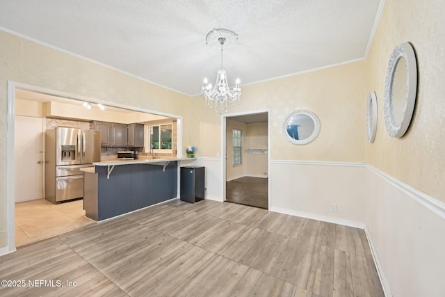 7437 Ortega Hills Dr, Jacksonville, FL 32244 - kitchen featuring stainless steel fridge with ice dispenser, a chandelier, a peninsula, a kitchen bar, and light countertops