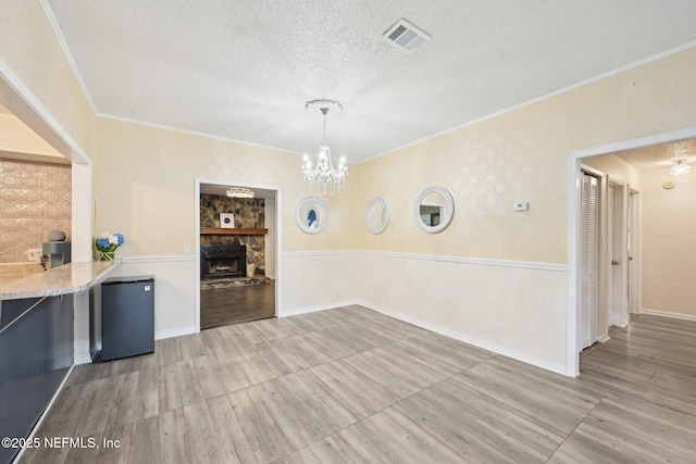 7437 Ortega Hills Dr, Jacksonville, FL 32244 - unfurnished dining area with ornamental molding, a textured ceiling, a chandelier, a stone fireplace, and wood finished floors