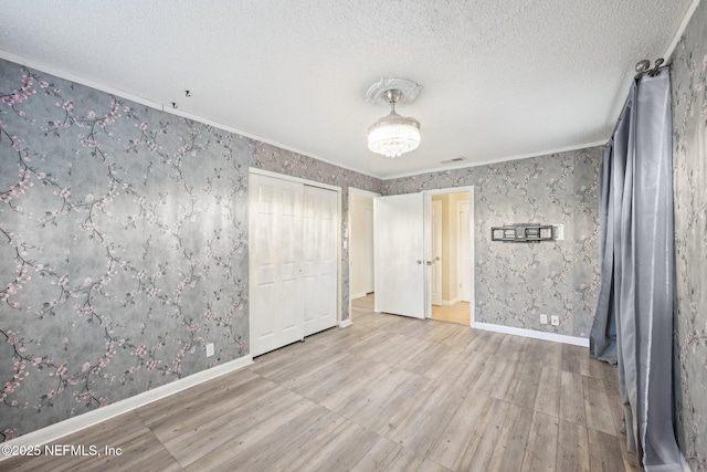 7437 Ortega Hills Dr, Jacksonville, FL 32244 - unfurnished bedroom featuring wood finished floors, wallpapered walls, baseboards, a textured ceiling, and ornamental molding