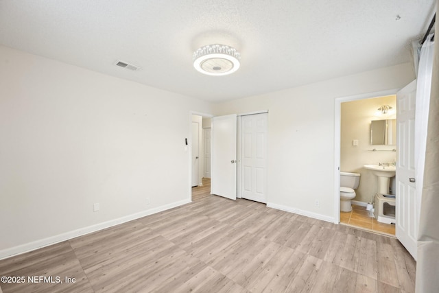 7437 Ortega Hills Dr, Jacksonville, FL 32244 - unfurnished bedroom with baseboards, light wood-type flooring, ensuite bathroom, and a closet