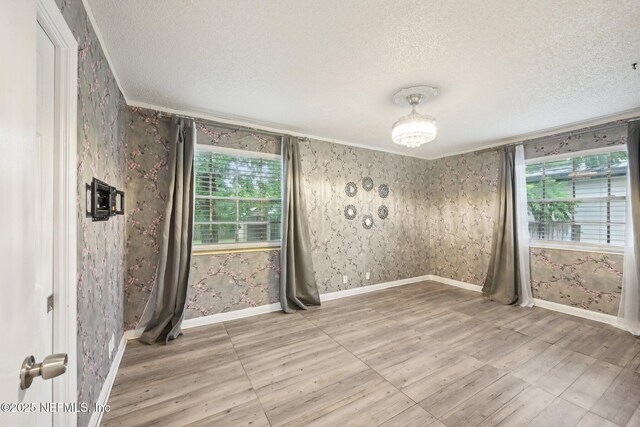 7437 Ortega Hills Dr, Jacksonville, FL 32244 - spare room featuring wallpapered walls, a textured ceiling, plenty of natural light, wood finished floors, and ornamental molding