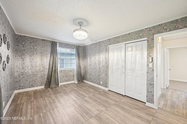 7437 Ortega Hills Dr, Jacksonville, FL 32244 - unfurnished bedroom with wood finished floors, wallpapered walls, a closet, a textured ceiling, and baseboards