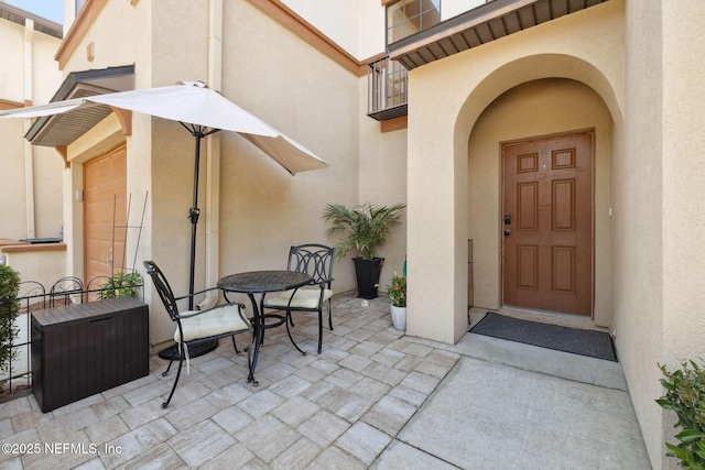 doorway to property featuring a patio, stucco siding, and outdoor dining space