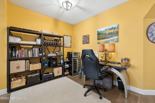 office space featuring a textured ceiling, baseboards, and wood finished floors