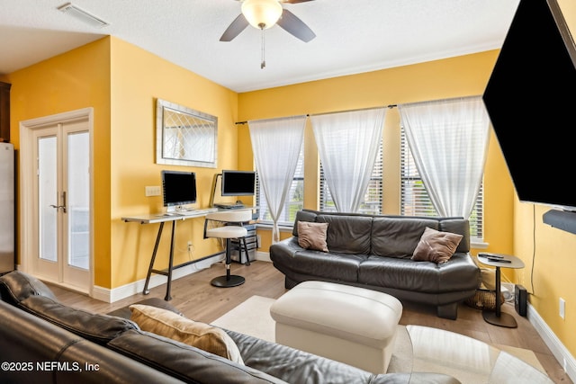 living area with baseboards, ceiling fan, visible vents, and wood finished floors
