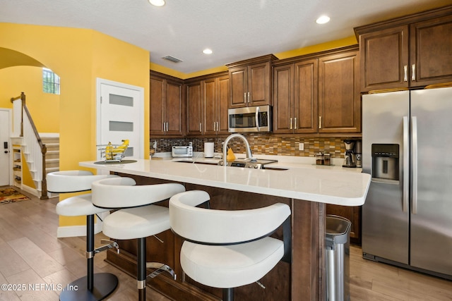 kitchen featuring visible vents, tasteful backsplash, a breakfast bar, and stainless steel appliances