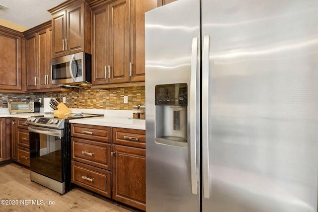 kitchen featuring visible vents, decorative backsplash, light wood-style floors, light countertops, and stainless steel appliances