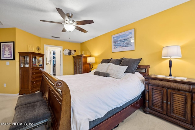 bedroom with visible vents, light carpet, baseboards, a walk in closet, and a ceiling fan