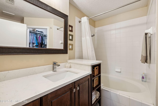 bathroom with a textured ceiling, visible vents, shower / bath combo, vanity, and a spacious closet