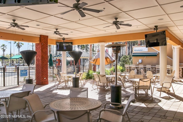 view of patio with fence, a ceiling fan, and outdoor dining space