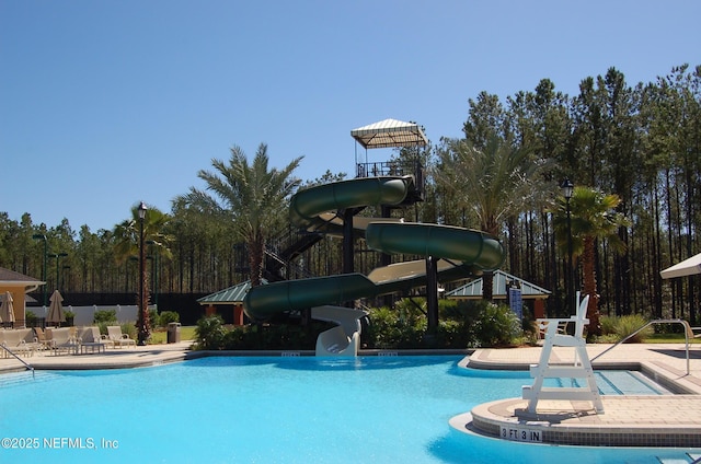 community pool featuring fence, a water slide, and a patio area
