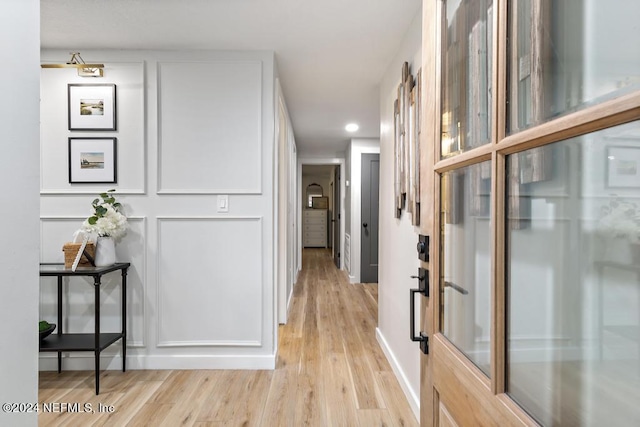 hallway featuring baseboards, light wood finished floors, and recessed lighting