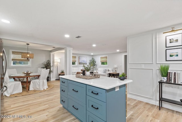 kitchen with light wood finished floors, recessed lighting, a kitchen island, ornate columns, and visible vents
