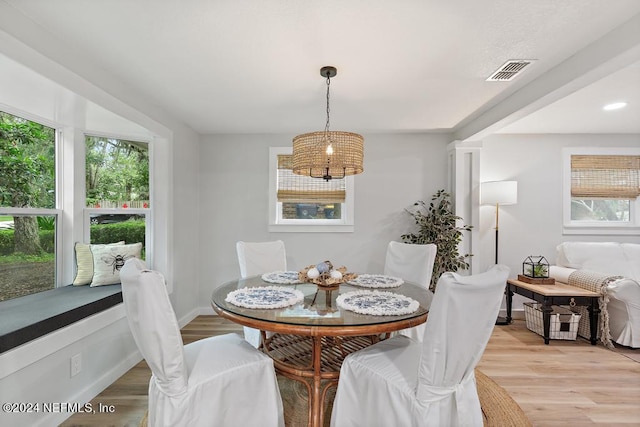 dining room featuring baseboards, visible vents, an inviting chandelier, and light wood finished floors