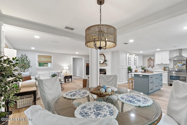 dining space with recessed lighting, visible vents, a large fireplace, and light wood-style flooring