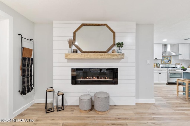 living area with recessed lighting, baseboards, a large fireplace, and light wood-style floors