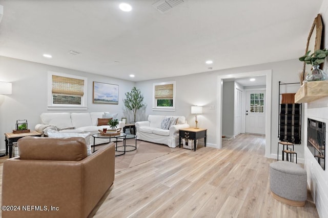 living area featuring recessed lighting, visible vents, light wood finished floors, and a fireplace