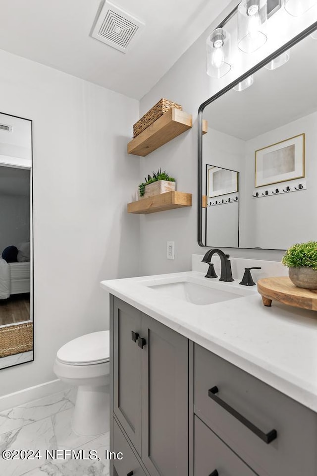 bathroom featuring vanity, toilet, marble finish floor, baseboards, and visible vents