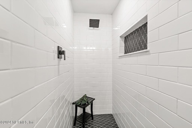 full bath with tile walls, tile patterned flooring, and a tile shower