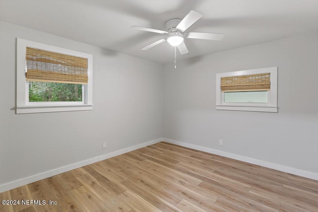 empty room featuring a ceiling fan, baseboards, and light wood-type flooring