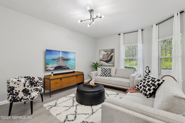 living area featuring baseboards, a textured ceiling, an inviting chandelier, and wood finished floors