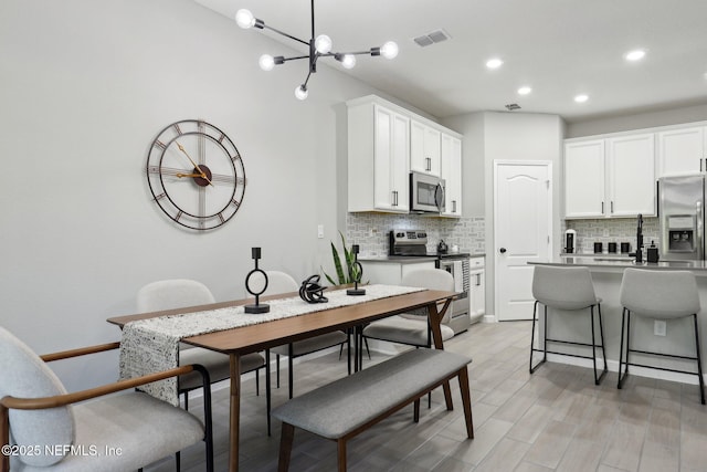 dining area with recessed lighting, a chandelier, visible vents, and light wood-type flooring