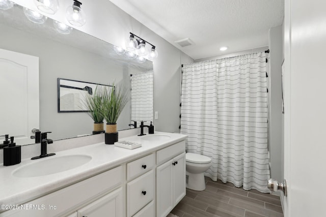 full bath with visible vents, a sink, toilet, and wood tiled floor