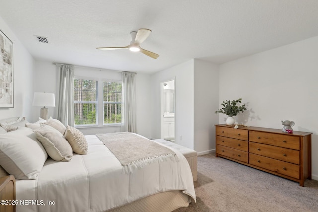 bedroom with ensuite bathroom, light carpet, ceiling fan, and visible vents