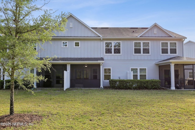 rear view of property featuring a lawn, board and batten siding, and a sunroom