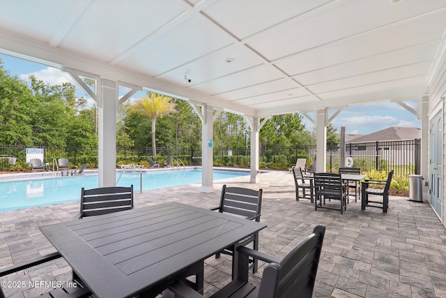 view of patio / terrace featuring a fenced backyard, outdoor dining space, and a community pool
