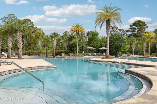 community pool with fence and a patio area