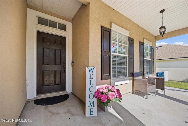 entrance to property with stucco siding and a porch
