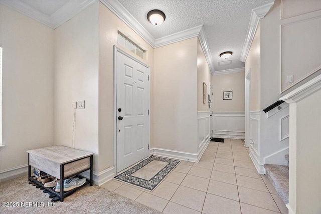 entrance foyer featuring ornamental molding, a textured ceiling, and light tile patterned flooring