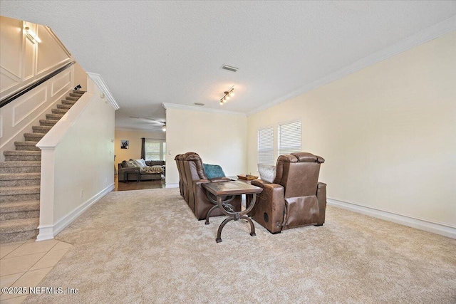 living area featuring crown molding, visible vents, stairs, light colored carpet, and a ceiling fan