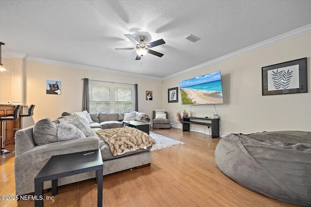 living room with crown molding, a ceiling fan, a textured ceiling, and light wood-style floors