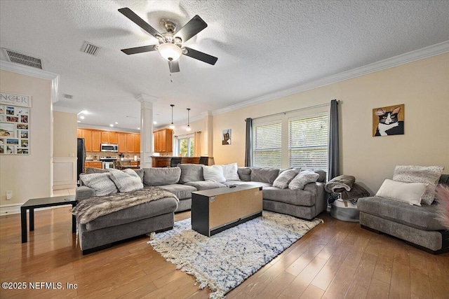 living area with crown molding, a ceiling fan, and visible vents