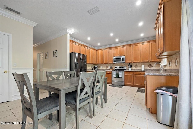 kitchen featuring light tile patterned floors, appliances with stainless steel finishes, crown molding, and visible vents