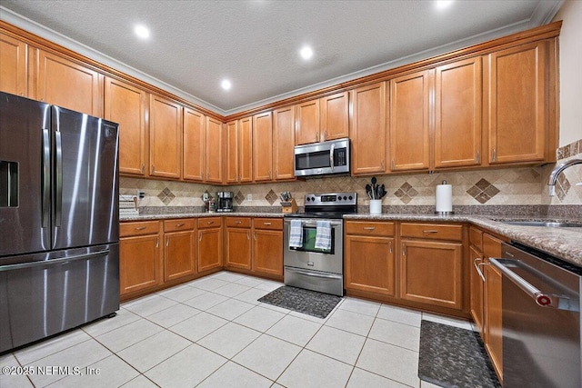 kitchen with light tile patterned flooring, a sink, brown cabinetry, stainless steel appliances, and tasteful backsplash